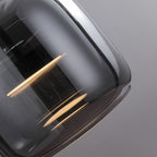 Close-up of a modern, glossy, dark gray pendant light glass lampshade with reflections of light strips on its smooth surface against a plain, light gray background.