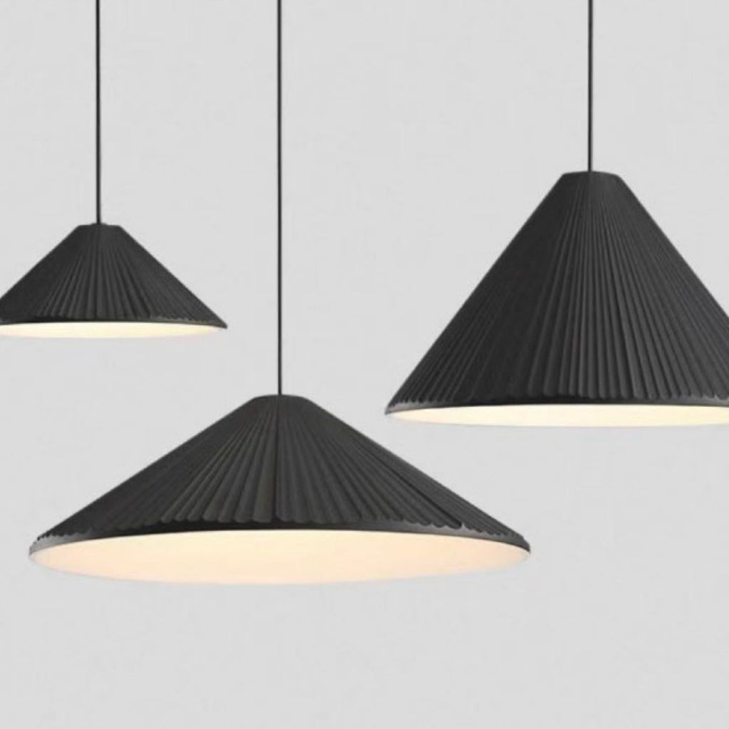 Three black, cone-shaped pendant lights with ribbed textures hang from the ceiling against a plain gray background. The pendant lights emit a soft white glow underneath.