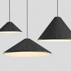 Three black, cone-shaped pendant lights with ribbed textures hang from the ceiling against a plain gray background. The pendant lights emit a soft white glow underneath.