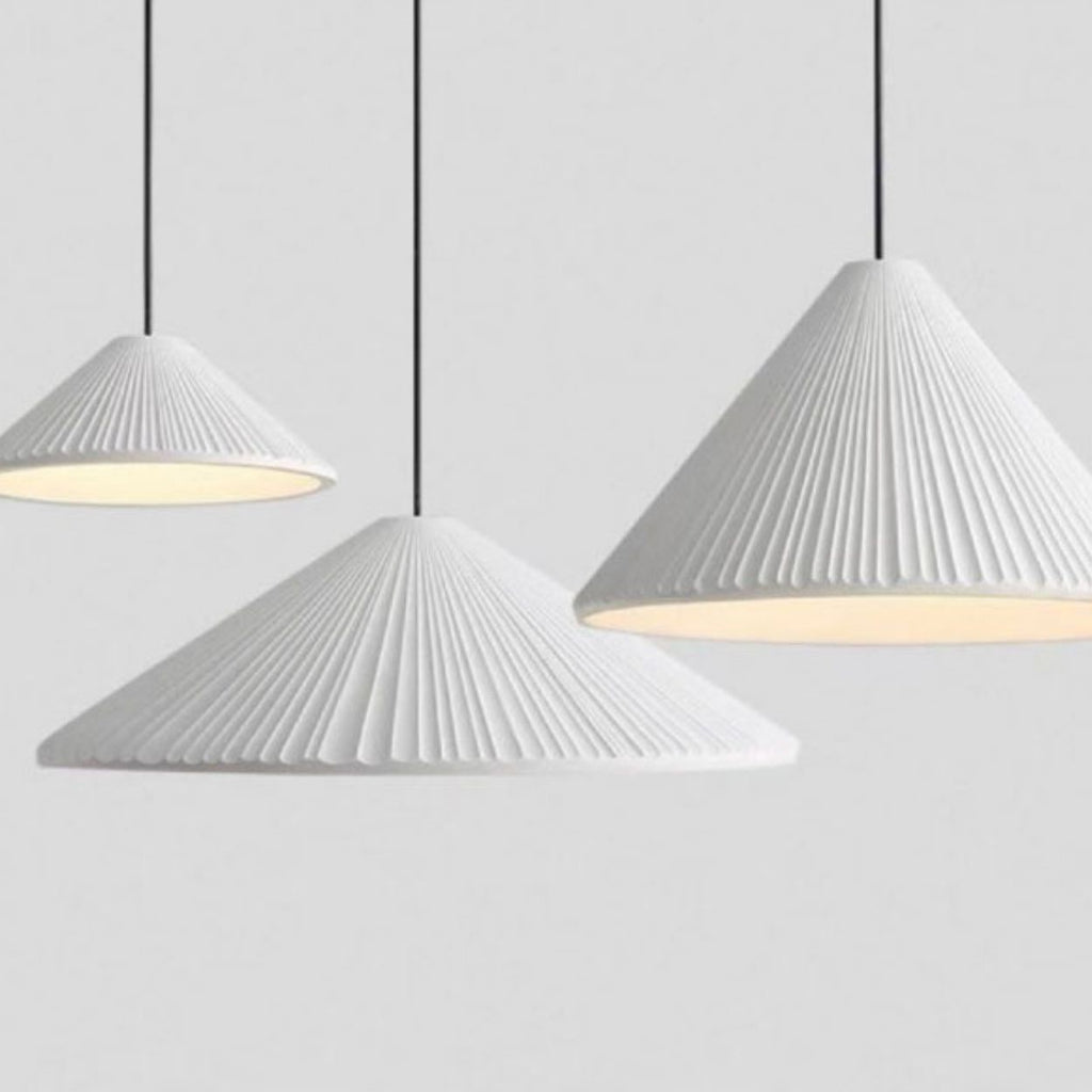 Three black, cone-shaped pendant lights with ribbed textures hang from the ceiling against a plain gray background. The pendant lights emit a soft white glow underneath.