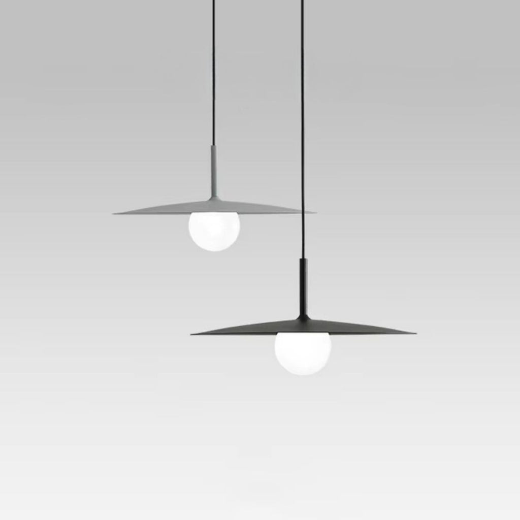 Two modern pendant lights hang from the ceiling, each featuring a flat, circular shade with a round white bulb beneath, set against a plain light gray background.