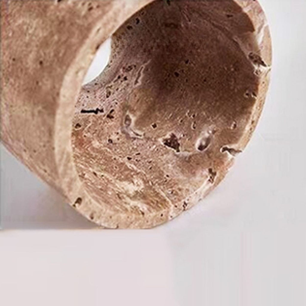 A close-up of a hanging pendant light fixture with a cylindrical, textured beige stone lampshade and an exposed bulb inside. The fixture is suspended from above against a plain light gray background.