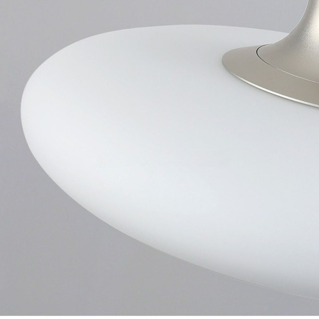Close-up of a modern, white, dome-shaped pendant light with a metallic base, set against a plain gray background.