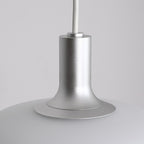 Close-up of a modern pendant light fixture with a matte silver metallic stem and a smooth, white, rounded shade against a plain light gray background—an elegant Pendant Light for contemporary spaces.