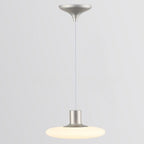 A modern pendant ceiling light with a silver fixture and a round, flat, frosted white shade hanging from a cord against a plain light gray background.
