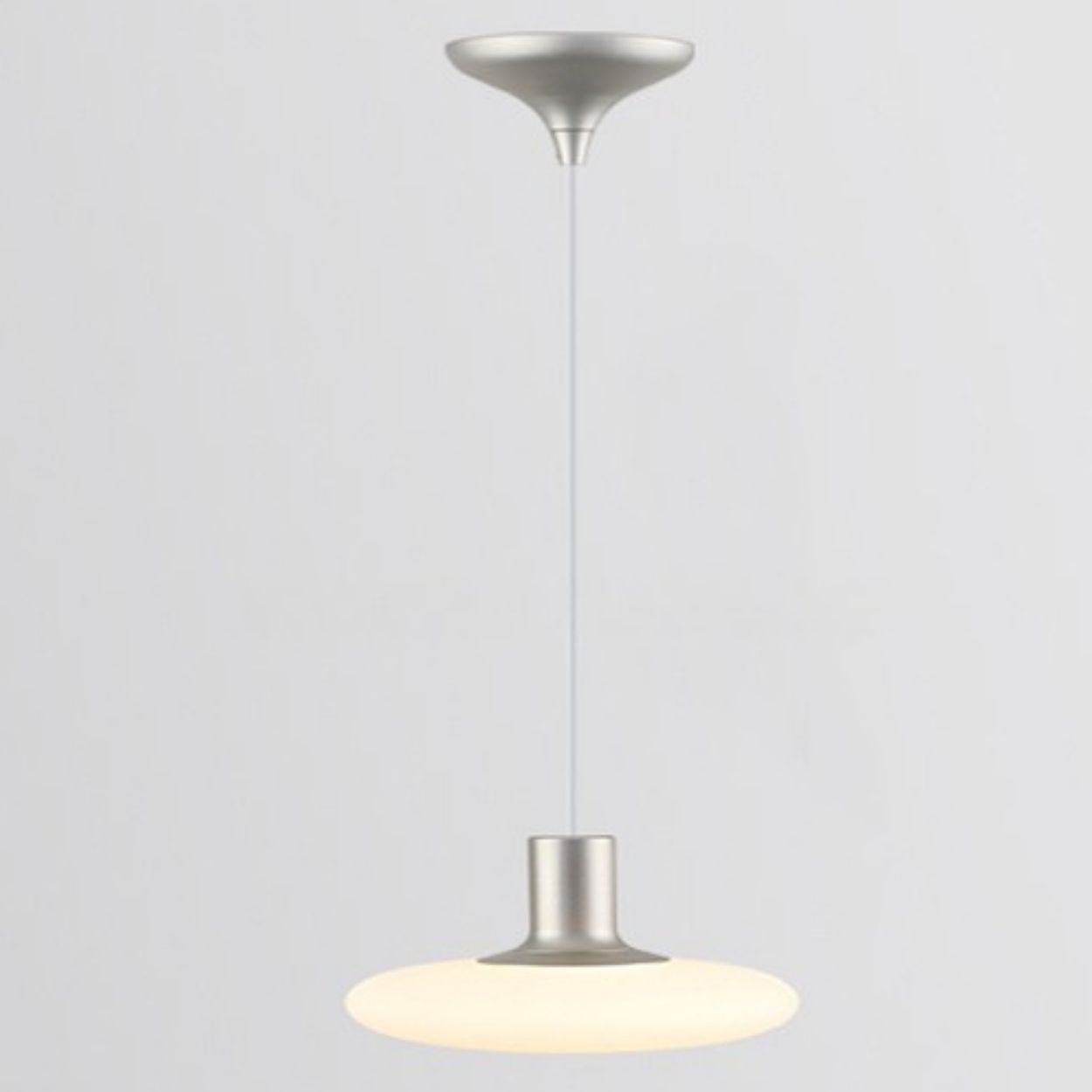 A modern pendant ceiling light with a silver fixture and a round, flat, frosted white shade hanging from a cord against a plain light gray background.