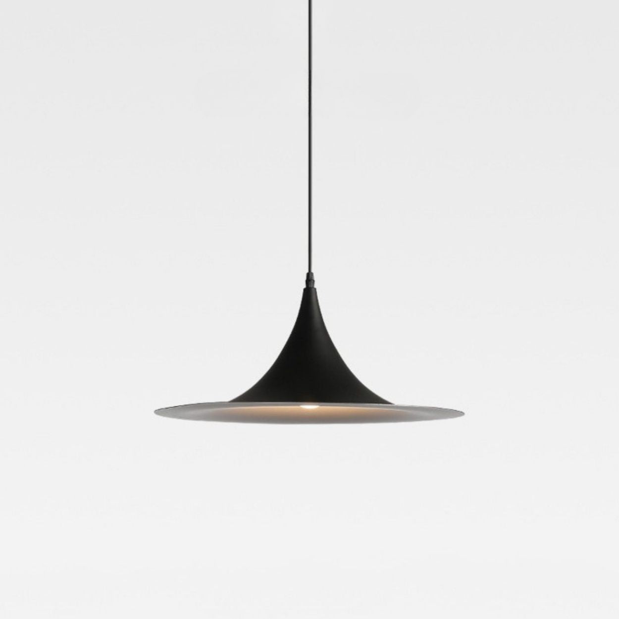 Minimalist black pendant light with a cone-shaped top and wide, flat bottom, suspended by a thin cord against a plain white background.