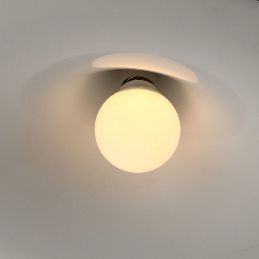 A glowing pendant light is mounted on a ceiling, casting a soft, warm light and creating circular shadows around it.