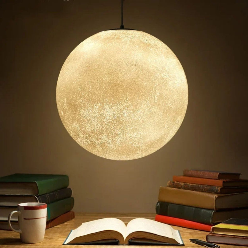 A glowing pendant light hangs above a wooden table with an open book, stacked books, and a white coffee cup, creating a cozy reading atmosphere.