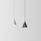 Two cone-shaped pendant lights hang from the ceiling against a plain light gray background; the left light is white and illuminated, while the right light is black and turned off.