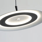 A modern, circular pendant ceiling light with a glowing ring design, this elegant pendant light emits soft white light and is suspended by a black cord against a plain light background.