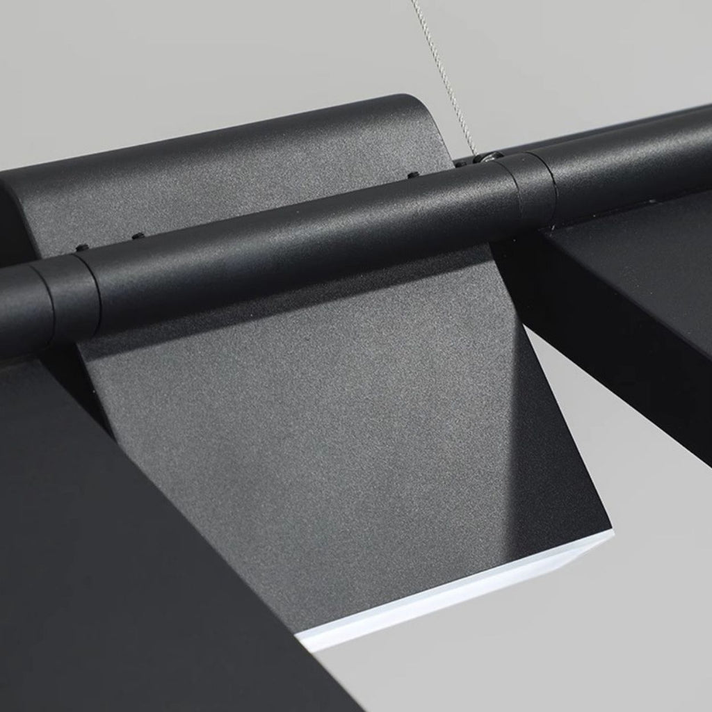 Close-up of a modern, black metal pendant light with a sleek, angular design and smooth surface, mounted on a light-colored wall or ceiling.