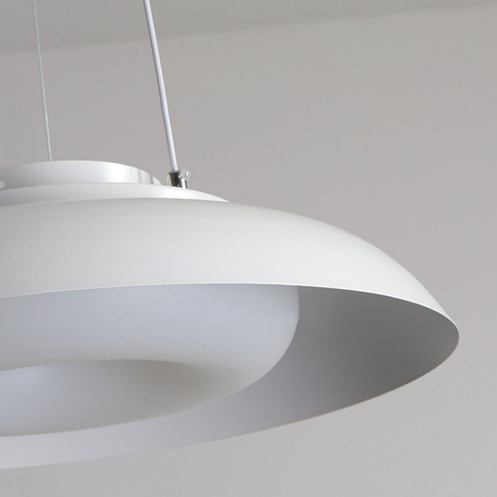 Close-up of a modern, circular white pendant light fixture with a smooth, minimalist design, hanging from thin wires. This ceiling light close up highlights its elegant form against a neutral background.