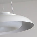 Close-up of a modern, circular white pendant light fixture with a smooth, minimalist design, hanging from thin wires. This ceiling light close up highlights its elegant form against a neutral background.