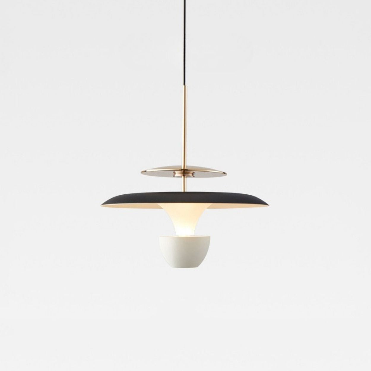 A modern pendant light with a black and gold circular shade, suspended by a thin black cord, features a white bowl-shaped diffuser beneath it, creating a striking look against the plain light gray background.