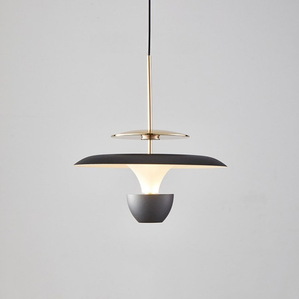 A modern luxury pendant light fixture with a black and gold finish, featuring a wide, flat shade and suspended from a black cord against a plain light gray background.