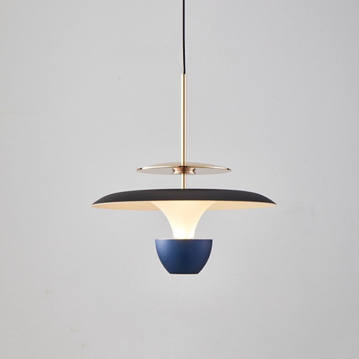 A modern pendant light luxury fixture featuring a black and gold circular shade, white inner diffuser, and blue bowl-shaped accent, elegantly suspended from a black cord against a plain light gray background.