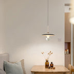 A cozy dining area with a light wood table, a vase of dried flowers, a cushioned bench, and a stylish pendant light overhead. Warm tones and soft lighting create a calm, minimalist atmosphere.