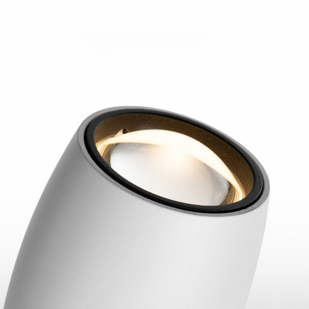 Close-up of a modern, cylindrical white spotlight with a black rim and a glowing bulb inside, resembling a sleek pendant light, set against a plain white background.