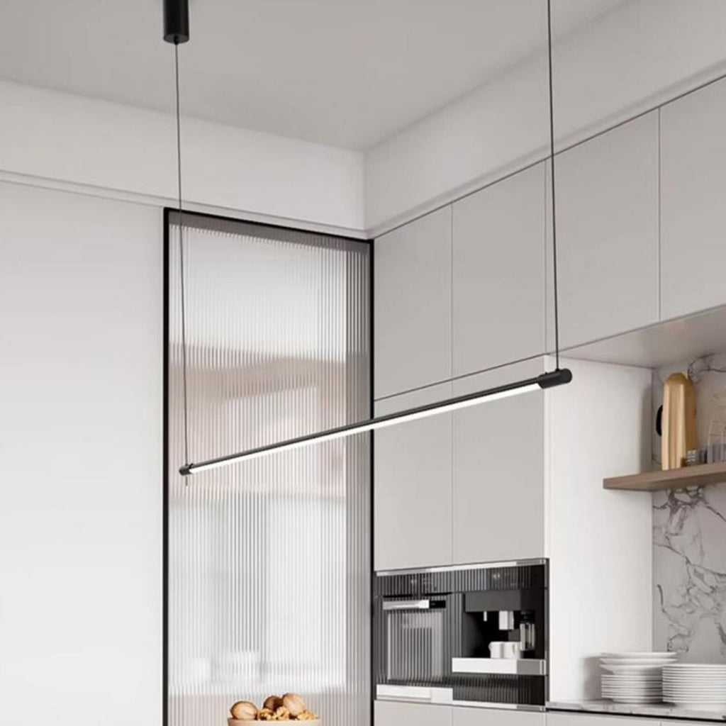 A modern kitchen features white cabinets, a built-in coffee machine, a marble backsplash, and a sleek pendant light illuminating the space. A bowl of bread sits on the counter, adding a touch of warmth to the contemporary design.