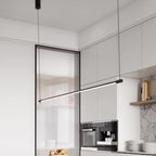A modern kitchen features white cabinets, a built-in coffee machine, a marble backsplash, and a sleek pendant light illuminating the space. A bowl of bread sits on the counter, adding a touch of warmth to the contemporary design.