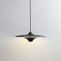 A modern black pendant light with a wide, flat shade hangs from the ceiling, casting a soft, warm glow on a plain white wall.