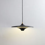 A modern black pendant light with a wide, flat shade hangs from the ceiling, casting a soft, warm glow on a plain white wall.