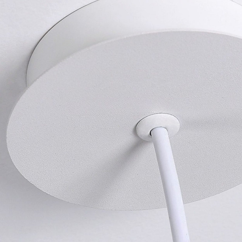Close-up of a round white pendant light mount with a white electrical cord extending downward, mounted against a white ceiling.