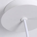 Close-up of a round white pendant light mount with a white electrical cord extending downward, mounted against a white ceiling.