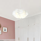 A modern white pendant light with a wavy design hangs from the ceiling in a room featuring white cabinets, pink walls, and framed artwork.