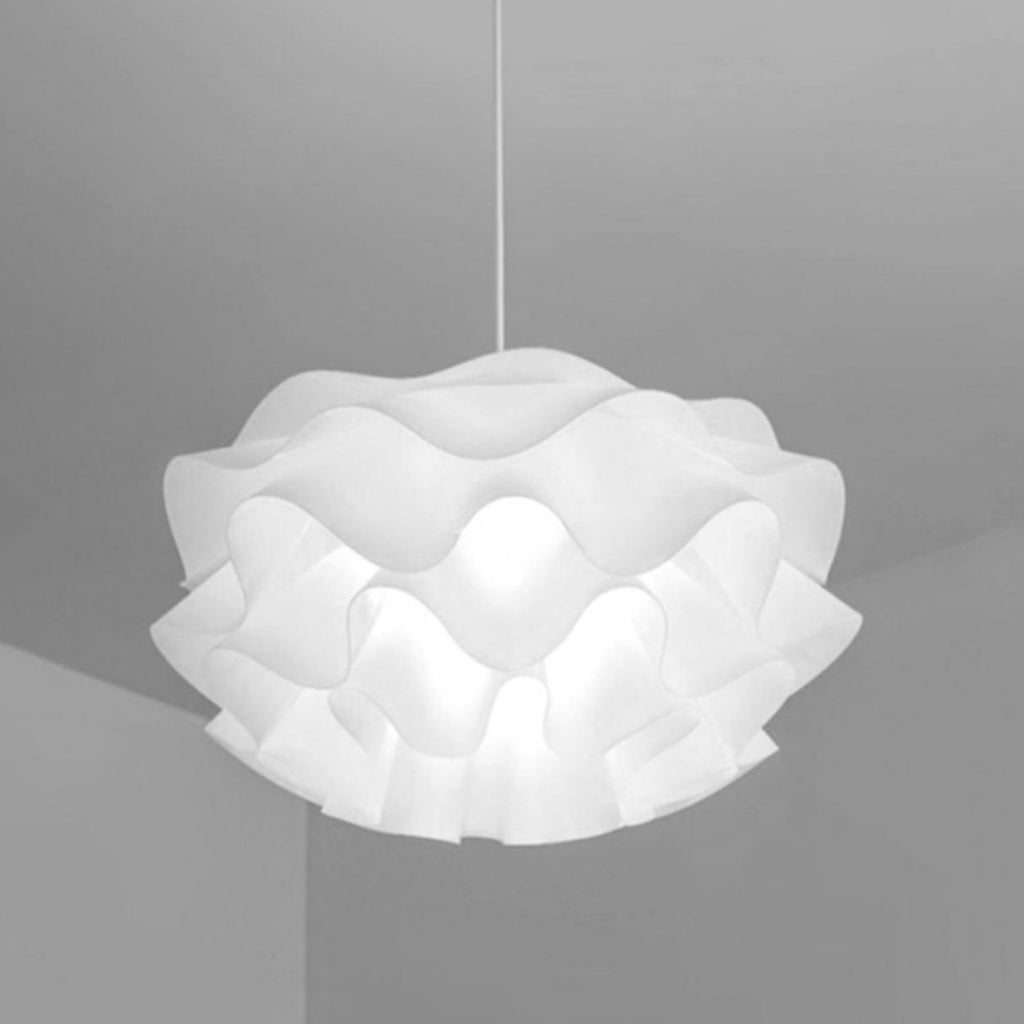 A stylish pendant light with a wavy, ruffled white lampshade hangs from the ceiling, adding a modern accent to the minimalist, light gray room.