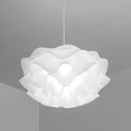 A stylish pendant light with a wavy, ruffled white lampshade hangs from the ceiling, adding a modern accent to the minimalist, light gray room.