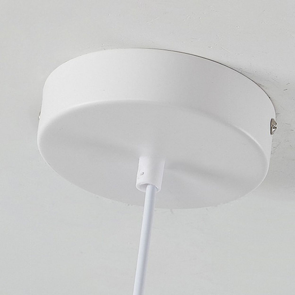 A close-up view of a round, white pendant light mount canopy with a white cord hanging down from its center, mounted on a white ceiling.