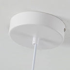 A close-up view of a round, white pendant light mount canopy with a white cord hanging down from its center, mounted on a white ceiling.