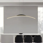 A modern dining room features a long white table, six black chairs, and a striking pendant light hanging above. Large windows with sheer curtains flood natural light into the minimalist space.