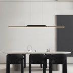 A modern dining room with a white table, four black chairs, and a striking pendant light above, featuring minimalist decor in neutral tones.