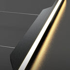 Minimalist abstract image featuring intersecting dark gray surfaces with sharp angles, accented by a diagonal, glowing, golden strip reminiscent of a pendant light close up amid subtle reflections. Thin white lines cross the background.