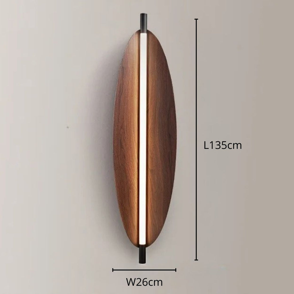 Vertical wall light featuring an oval wooden body and a central light strip, mounted on a neutral wall. Dimensions are labeled: 135 cm tall and 26 cm wide.