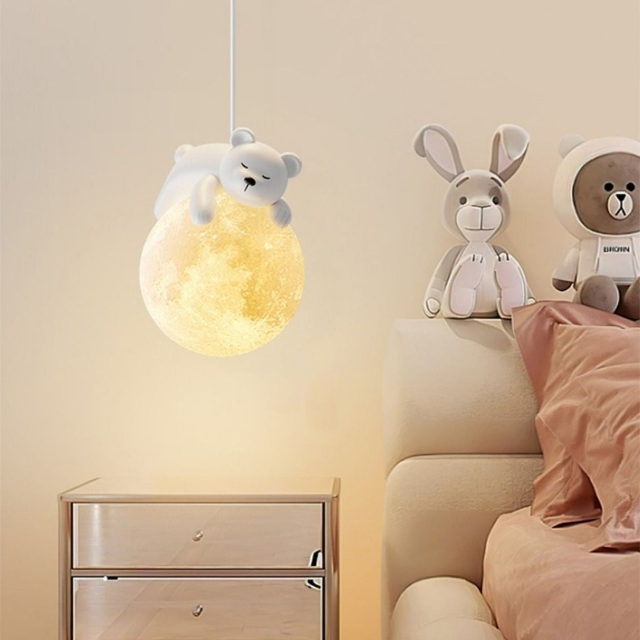 A cozy bedroom features a teddy bear-shaped pendant light hanging above the bedside table. Plush toys, including a rabbit and bear, rest on the bed with a pink pillow and beige bedding, all softly illuminated by warm lighting.