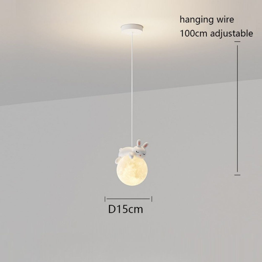 This pendant light features a white hanging wire (100 cm adjustable) and a round, glowing lamp (15 cm diameter), topped with a charming white rabbit figure. The playful lamp is elegantly suspended from a white ceiling.