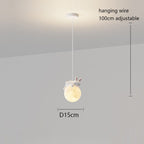 This pendant light features a white hanging wire (100 cm adjustable) and a round, glowing lamp (15 cm diameter), topped with a charming white rabbit figure. The playful lamp is elegantly suspended from a white ceiling.