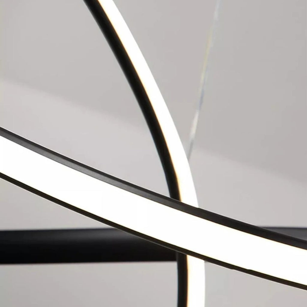 A close-up view of intersecting curved LED light strips against a neutral background, creating an abstract, modern pendant light close up with bright white illumination.