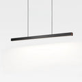A modern, black pendant light hangs from the ceiling by two thin cords, illuminating a white background with a soft glow.