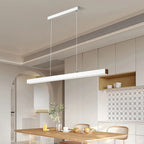 A modern, minimalist kitchen features light wood furniture and a striking rectangular pendant light above the table. Built-in cabinets with patterned backsplash tiles complete the look, with a few tableware items and a glass bottle on the table.