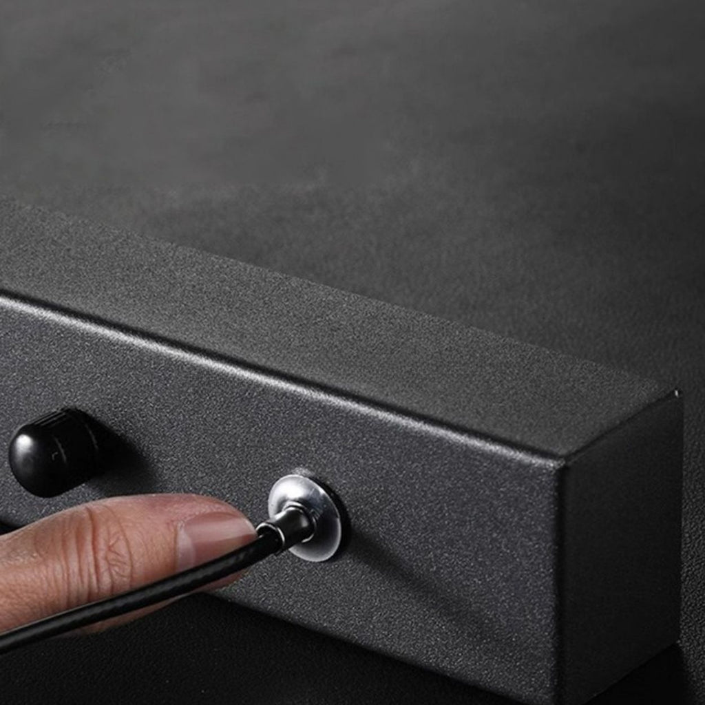 A close-up view of a rectangular object with a black top and white side, possibly a minimalist desk organizer or box, placed on a white surface. The grayscale image evokes the clean lines of a pendant light close up.