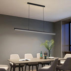 A modern dining room with a rectangular table, six chairs, a stylish pendant light above, an open book, bottles, and a plant on the table, complemented by a large window in the background.